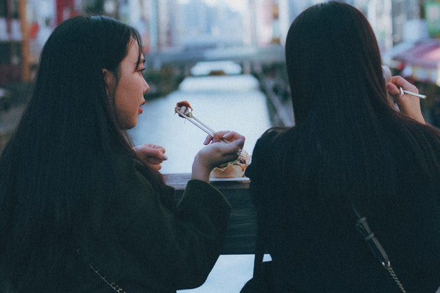 Dve ženy obedujú na ulici s paličkami
